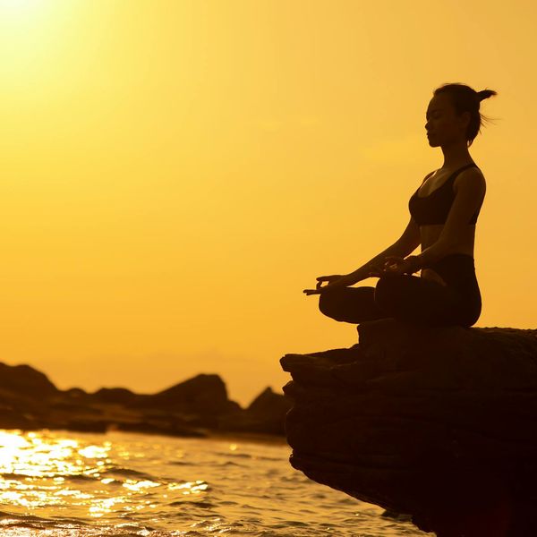 A silhouette of a person in a powerful yoga warrior pose at sunset.